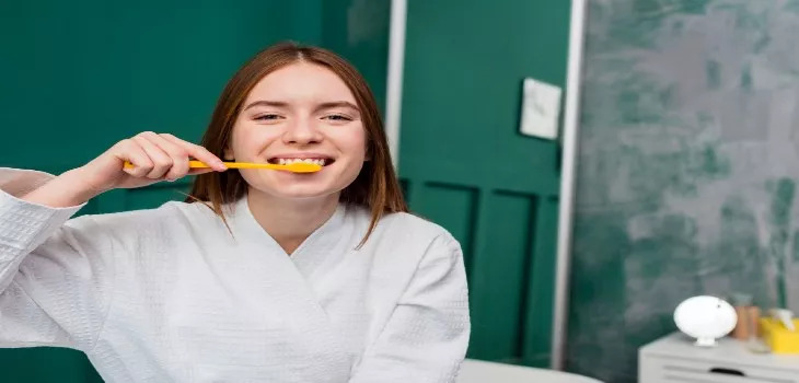 a woman is brushing her teeth to prevent tooth decay