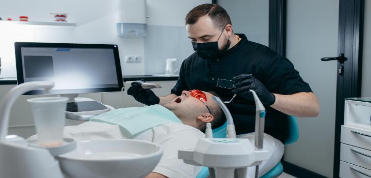 Dentist scanning teeth of male patient with modern scanning 3d machine